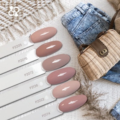 Seis amostras de verniz de unhas em tons nude junto a saco de palha e calças de ganga azuis