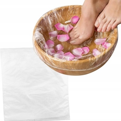 Pés femininos num banho de tigela de madeira com pétalas de rosa e saco plástico branco