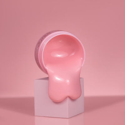 Pote rosa com creme cor de rosa sobre cubo branco em fundo rosa com texto SAUTE NAILS