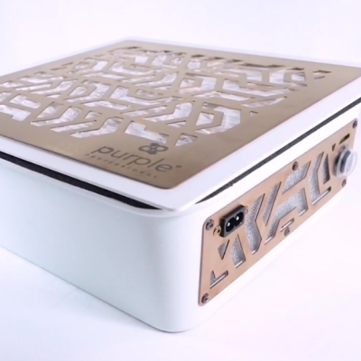 Dispositivo eletrônico branco com painéis metálicos dourados ornamentados e entrada de energia