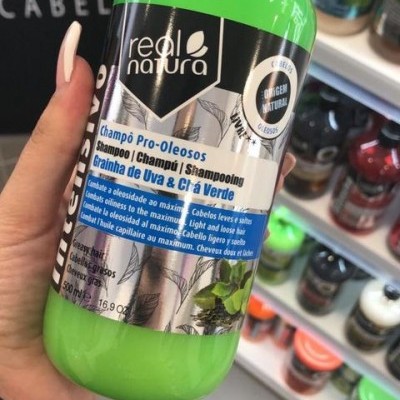Frasco verde de champô Raiz Natura Pro-Oleosos com selo de origem natural e texto em várias línguas
