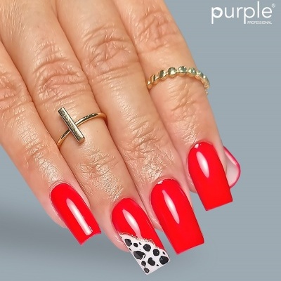 Mão feminina com unhas vermelhas brilhantes e um anel dourado, destaque para unha com padrão branco e preto.