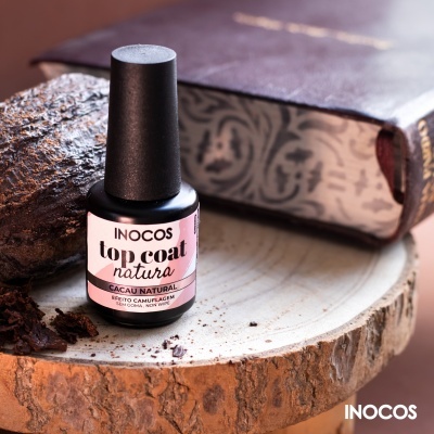 Frasco de verniz INOCOS top coat natura Cacau Natural sobre madeira com cacau e livro antigo
