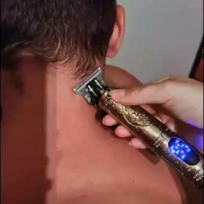 Máquina de cortar cabelo metálica dourada com LEDs azuis a aparar nuca.