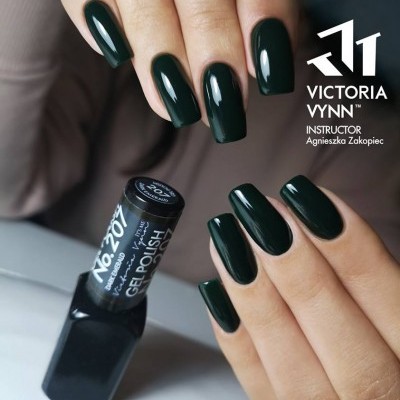 Mãos com unhas pintadas de verniz gel verde escuro brilhante ao lado de frasco de verniz gel preto