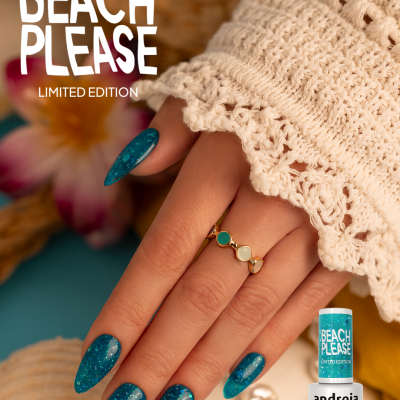 Mão com unhas pintadas de verniz gel azul glitter Beach Please, anéis dourados, creme de malha branca e conchas de fundo