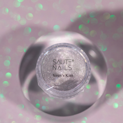 Pote de glitter prateado SAUTE NAILS Siren's Kiss sobre fundo rosa brilhante