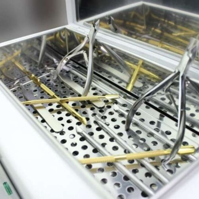 Caixa esterilizadora metálica com instrumentos médicos e espelho