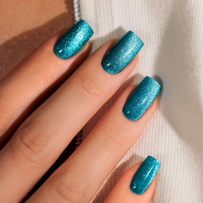 Unhas azuis metálicas brilhantes em mãos femininas segurando tecido branco