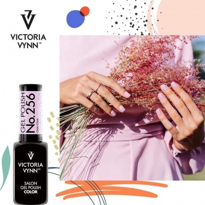 Verniz gel Victoria Vynn No. 256 em embalagem preta com tampa rosa clara e mãos com unhas rosa claro segurando flores secas