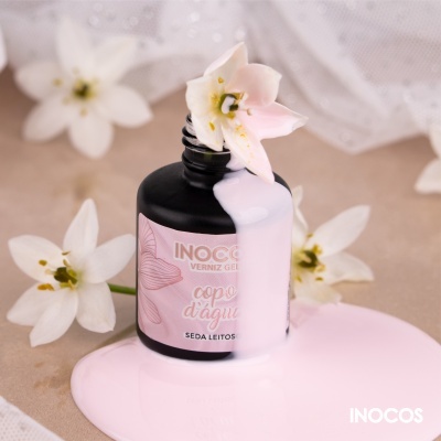 Frasco preto de verniz gel INOCOS com rótulo rosa e verniz rosa derramado