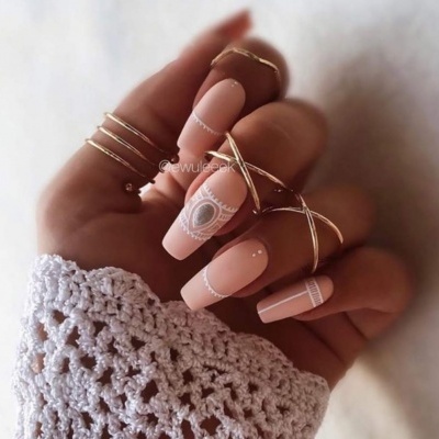 Unha nude com desenhos brancos e argolas douradas