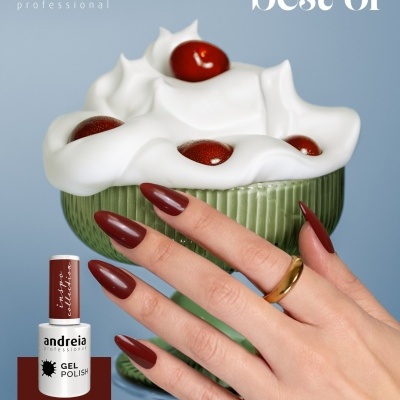 Mão feminina com unhas castanhas avermelhadas segurando uma taça verde com creme branco e bolas vermelhas ao lado de frasco de verniz gel da andreia professional.