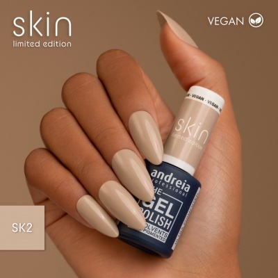 Mão com unhas pintadas de verniz bege nude segurando frasco de verniz de gel azul escuro