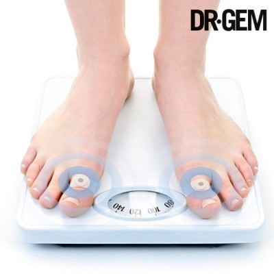 Balança de pesagem branca com mostrador analógico e pés descalços em cima