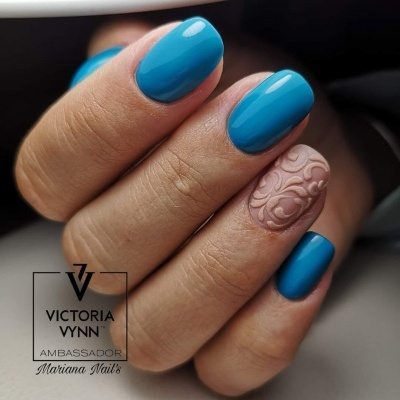 Unhas pintadas de azul com uma unha nude texturizada, com texto Victoria Vynn Ambassador Mariana Nails