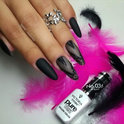 Unhas pretas foscas e decoradas com verniz brilhante, frasco de verniz Victoria Vynn, penas rosa e pretas ao fundo