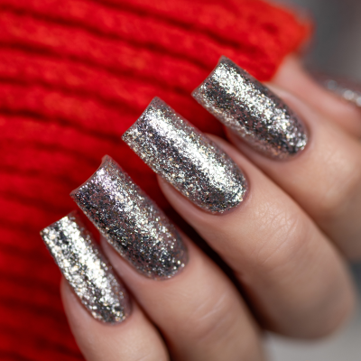 Unhas com verniz glitter prateado em fundo vermelho de tecido