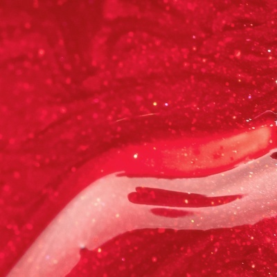 Close-up de produto vermelho e branco com textura brilhante e partículas cintilantes