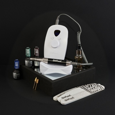 Dispositivo elétrico branco com caneta preta e frascos de verniz junto a limas e adaptador