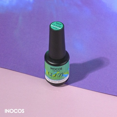 Frasco de verniz para unhas INOCOS Top Coat Glaze sobre fundo roxo e rosa claro