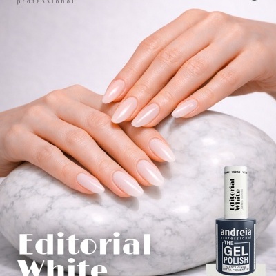 Mãos femininas com unhas brancas suavemente alongadas junto a frasco de verniz de gel preto em fundo branco com pedra mármore.