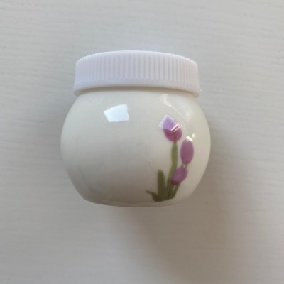 Frasco branco com tampa branca e decalque de tulipas lilases.