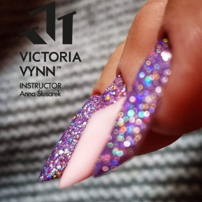 Unhas artificiais com glitter roxo e unha nude com texto Victoria Vynn e instrutora