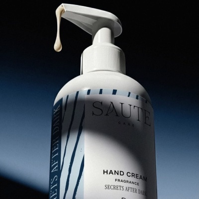 Frasco de creme para as mãos branco com doseador e texto no rótulo.