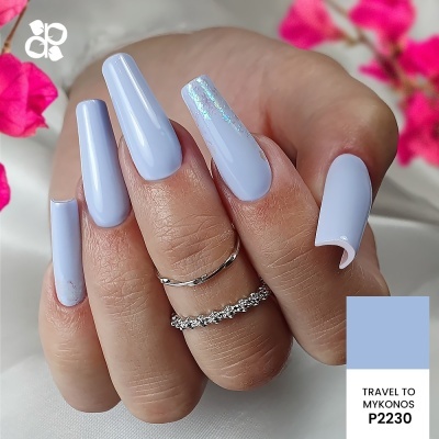 Unhas artificiais azul claro com decoração prateada e anéis na mão