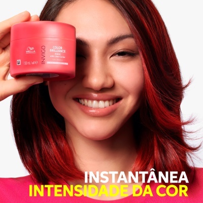 Frasco vermelho de máscara capilar Wella próximo a mulher com cabelo vermelho