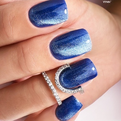 Unhas postiças azuis com anel prateado e fundo claro