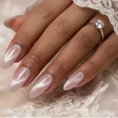Mão com unhas compridas rosa cintilante e anel com pedra sobre renda branca