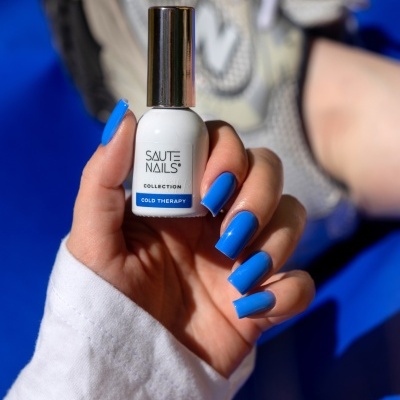 Frasco de verniz para unhas branco com tampa metálica e unha pintada de azul