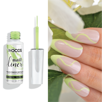 Frasco aberto de esmalte verde pastel INOCOS ao lado de unhas com decoração ondulada verde pastel sobre base rosa, com folhas e flores ao fundo.