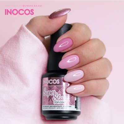 Mão segurando frasco de verniz de unhas Inocos Super Sea Top Coat com unhas rosa
