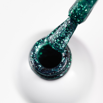 Frasco de verniz para unhas verde cintilante aberto com pincel a retirar verniz.