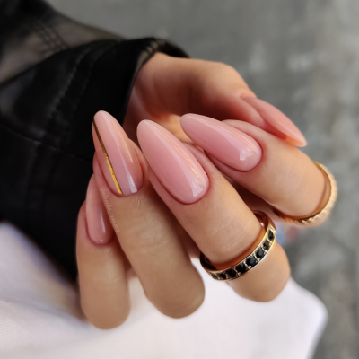 Unhas compridas em verniz rosa brilhante com decoração dourada e anéis