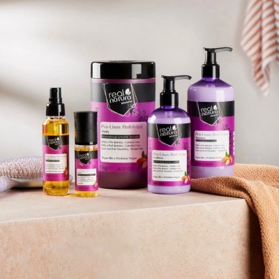 Produtos para cabelo Real Natura Pro-Lisos Anti Frizz em embalagens roxas e pretas sobre superfície clara com escova e toalha