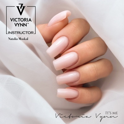 Mão feminina com unhas artificiais rosa pálido brilhante sobre tecido branco