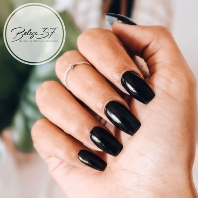 Mão com unhas longas pintadas de preto e argolas finas prateadas.