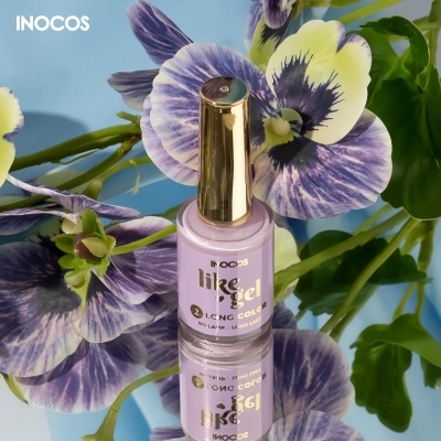 Frasco de verniz de unhas lilás da marca INOCOS com tampa dourada entre flores coloridas