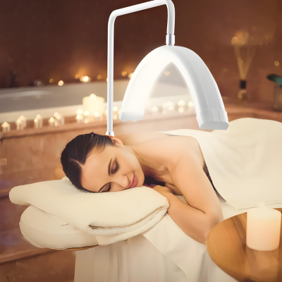 Mulher deitada em cama de massagem com dispositivo branco acima do rosto, velas acesas ao fundo