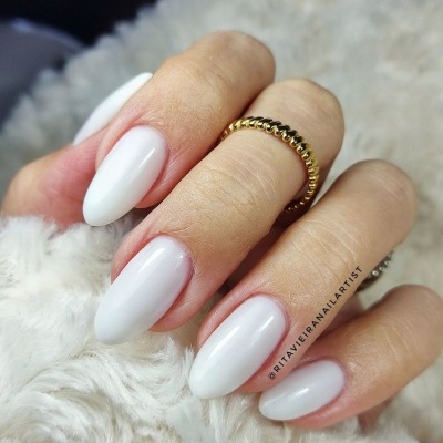Mão com unhas brancas amendoado e anel dourado