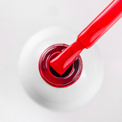 Frasco branco de verniz de unhas com pincel vermelho a retirar verniz