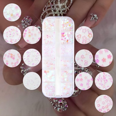 Conjunto de decoração para unhas com formas pequenas em rosa e branco numa caixa dividida.