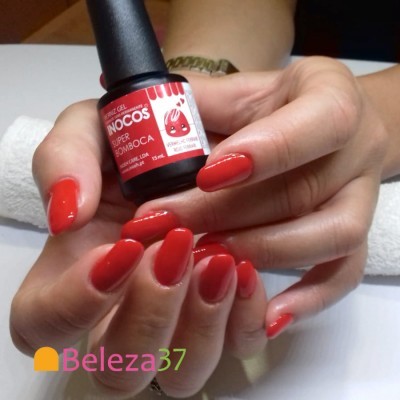 Verniz gel vermelho vivo INOCOS em mãos femininas sobre fundo branco