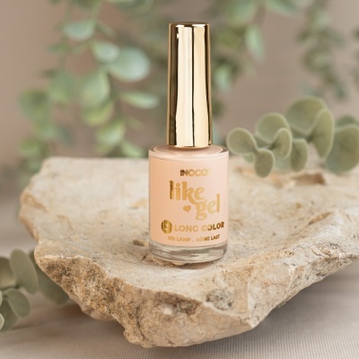 Frasco de verniz para unhas nude da marca BNCO sobre pedra rústica com folhagem verde ao fundo