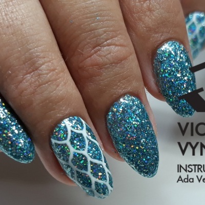 Unhas compridas decoradas com glitter azul e padrão branco