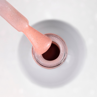 Frasco aberto de verniz para unhas cor rosa com glitter e pincel embebido 